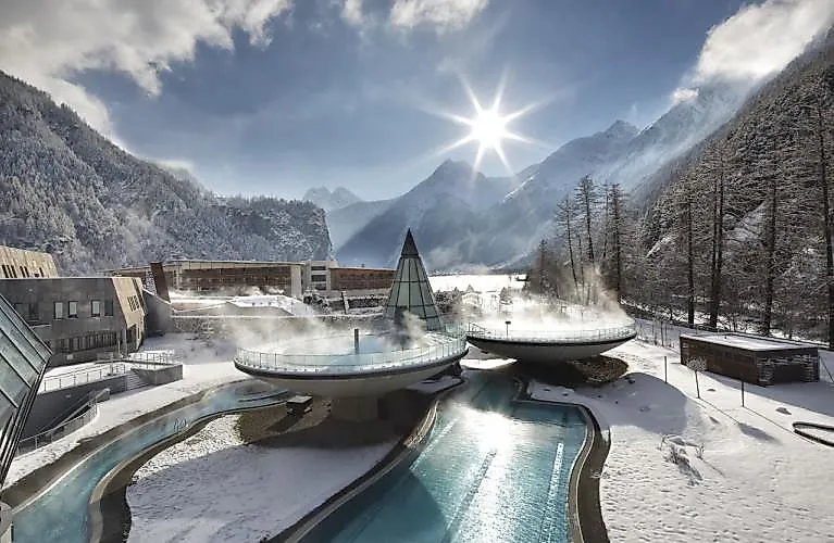 Dampfen steigt aus den Außenpools der Aqua Dome Therme in Längenfeld im verschneiten Winterpanorama.