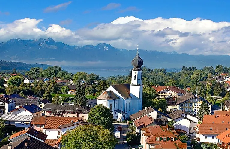 Sommerlicher Blick über Bad Endorf mit Kirche und Alpenpanorama im Hintergrund