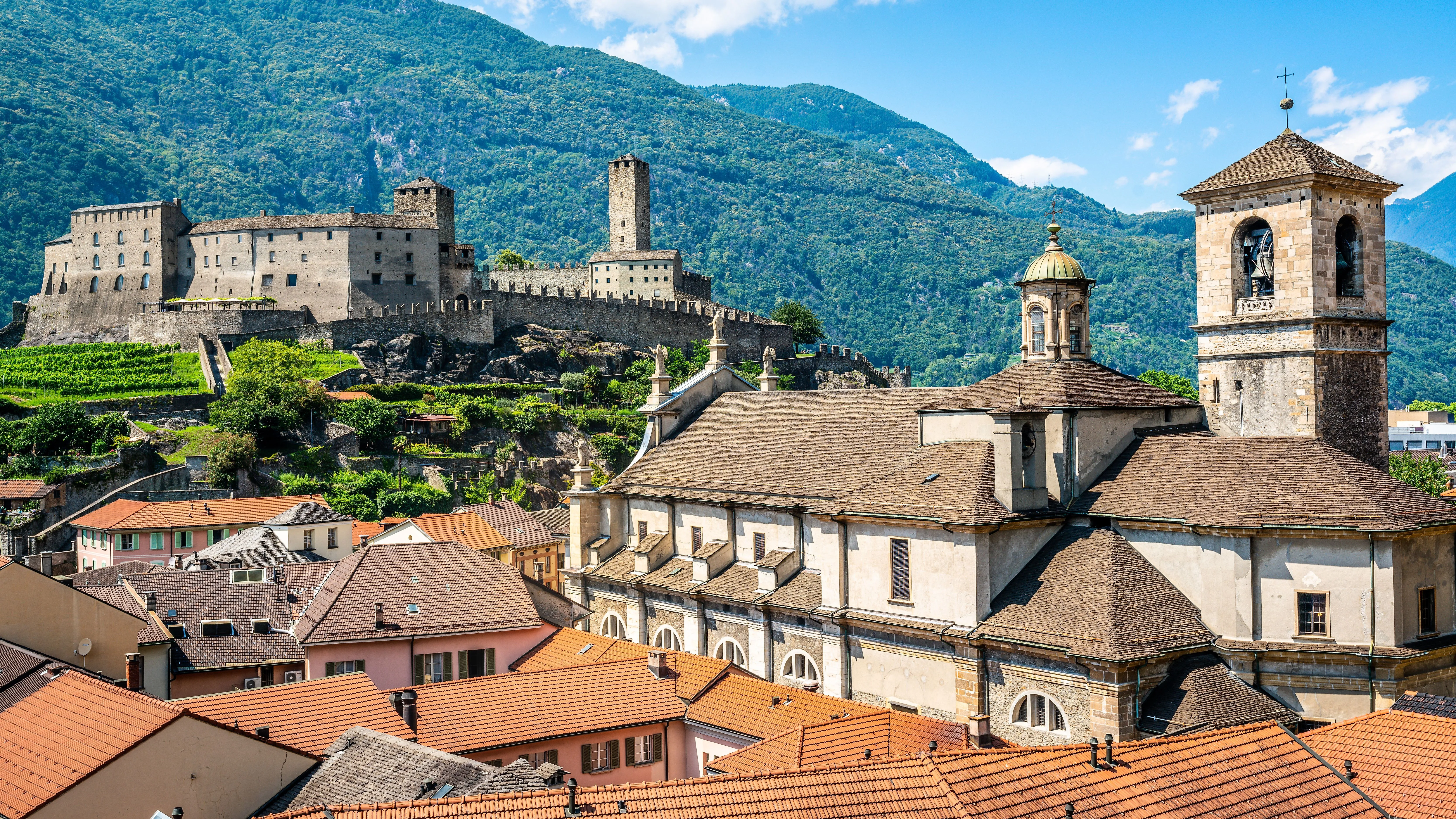 Historisches Castelgrande in Bellinzona, Schweiz, vor einer Kulisse aus grünen Bergen und roten Ziegeldächern