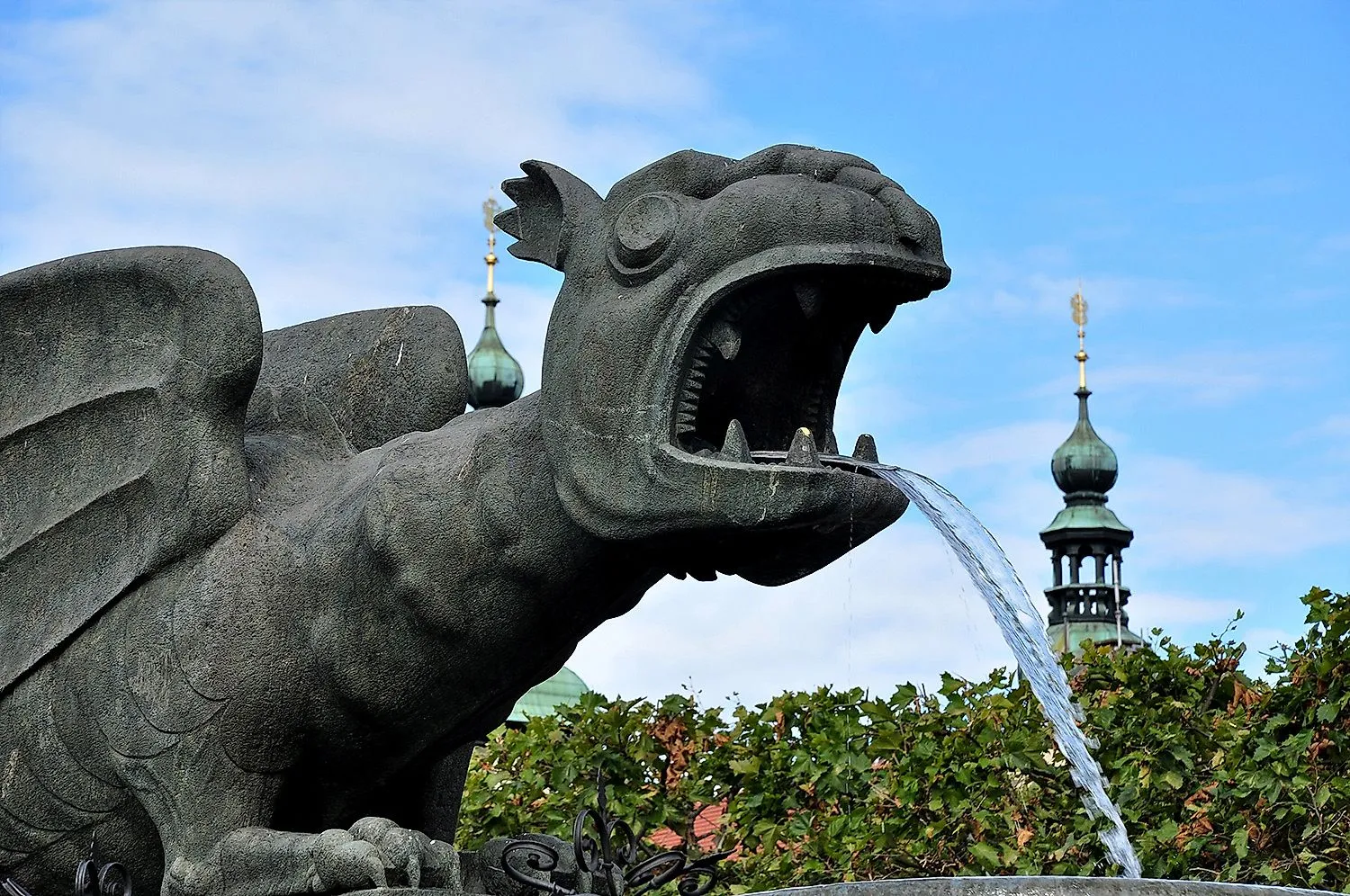 Fontaine Lindwurm à Klagenfurt avec jet d'eau et tours en arrière-plan