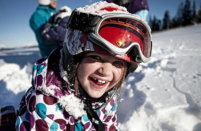 Fröhliches Kind mit Skibrille im Schnee am Skigebiet Marienberg in Biberwier
