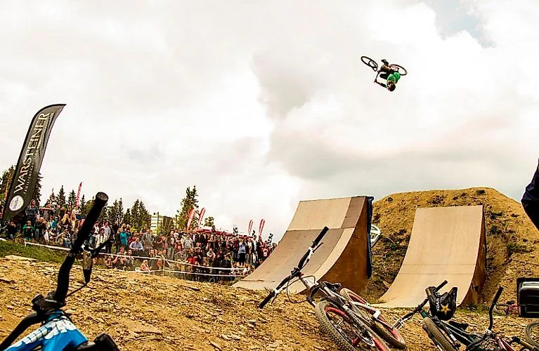 Un ciclista de montaña salta espectacularmente por encima de una rampa ante el público en un evento celebrado en el Bike Arena Sauerland de Winterberg.