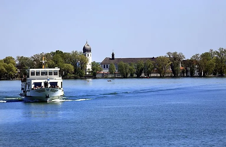Ausflugsschiff auf dem Chiemsee vor der Fraueninsel mit barocker Kirche, bei strahlendem Wetter im Frühling