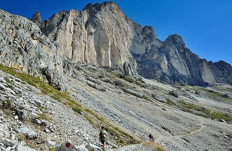 Wandelaars onder imposante rotswanden in Carezza in de Dolomieten bij schitterend zomerweer