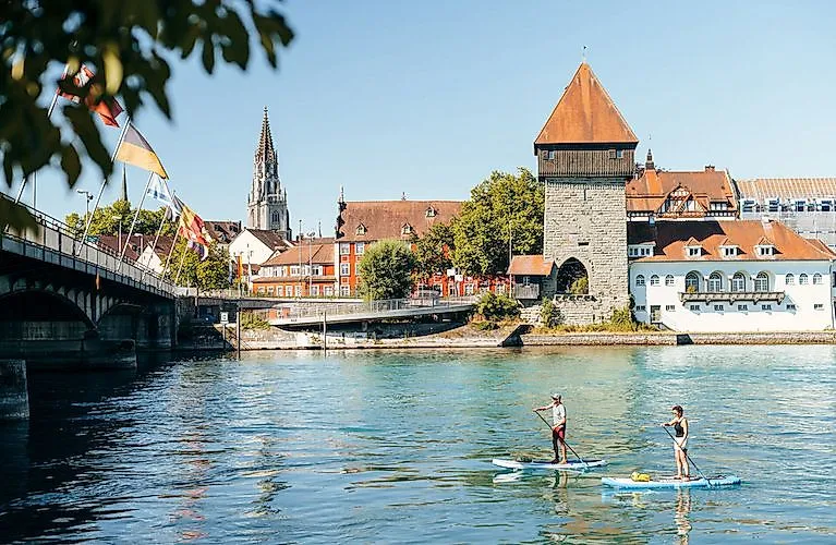Zwei Personen paddeln auf dem Seerhein vor dem Rheintorturm in Konstanz