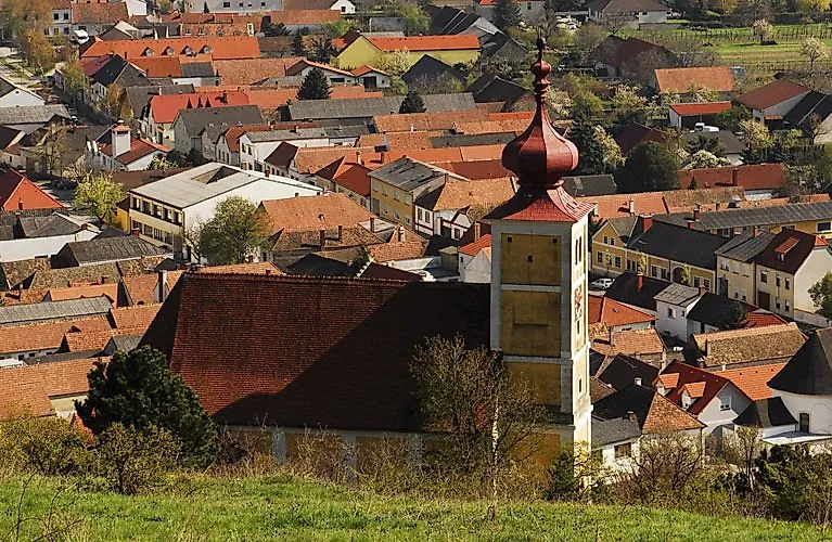 Historische Kirche mit rotem Zwiebelturm über den Dächern eines burgenländischen Orts