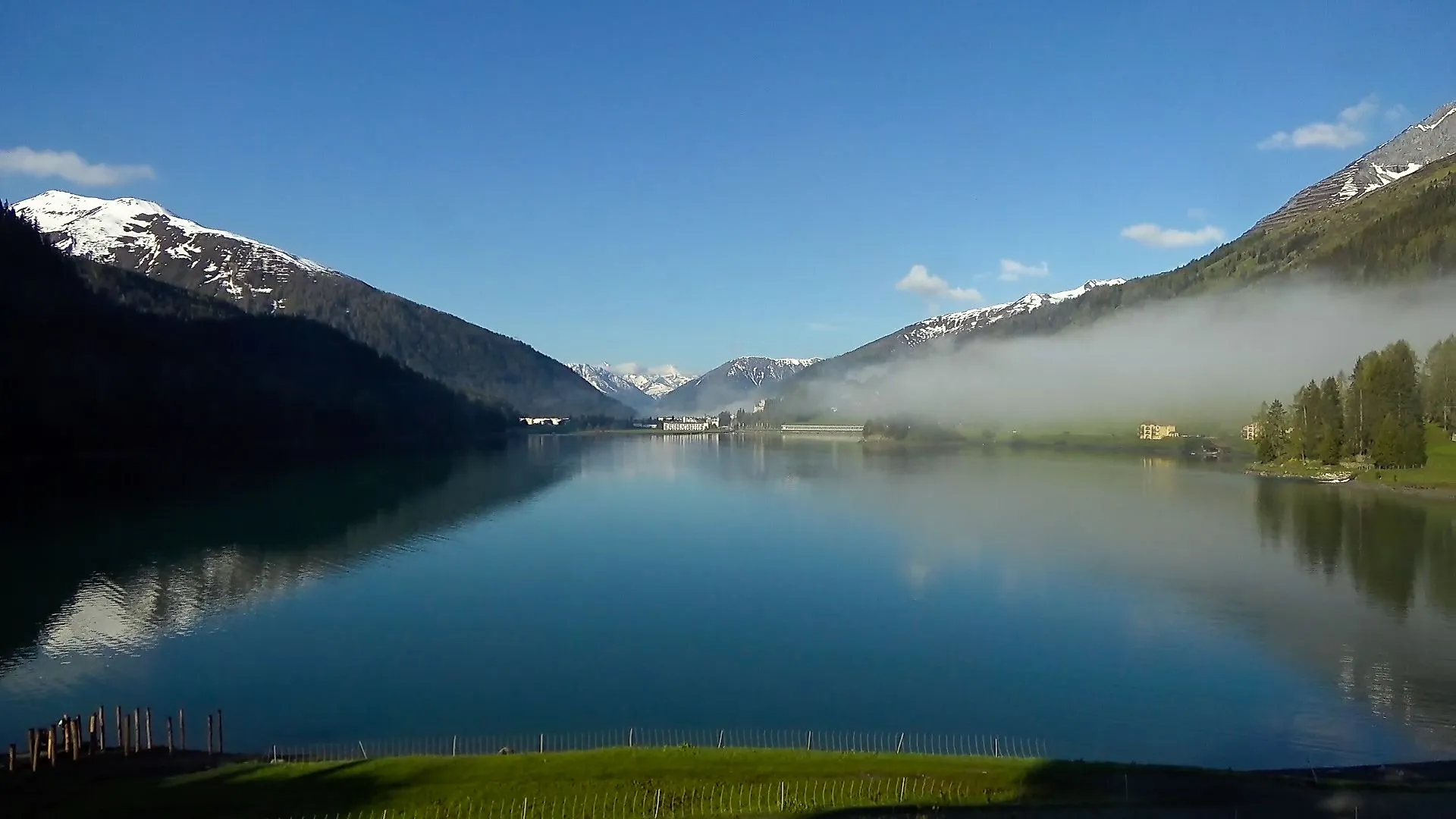 Nebel hängt über dem Davosersee in Davos Wolfgang an einem sonnigen Frühlingsmorgen