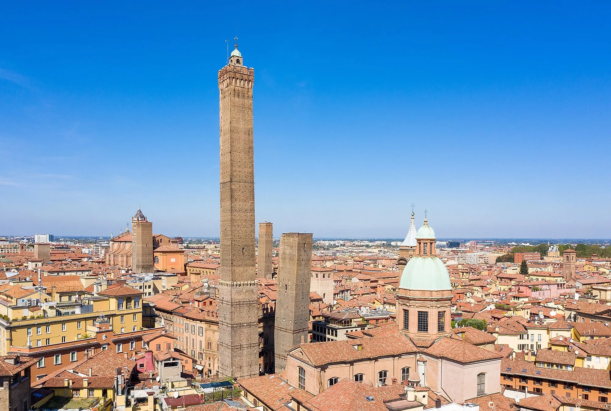 Historische Altstadt von Bologna mit Asinelli-Turm und roten Ziegeldächern unter blauem Himmel
