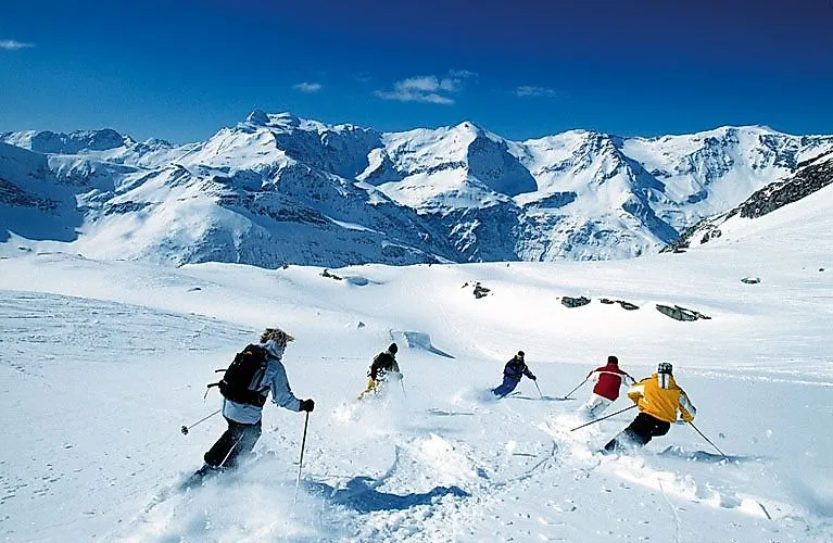Skifahrer fahren durch frischen Pulverschnee im Gasteiner Tal, umgeben von den verschneiten Gipfeln der Hohen Tauern.