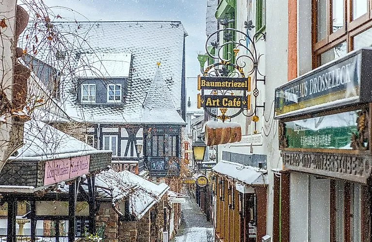 Winterliche Drosselgasse in Rüdesheim mit verschneiten Fachwerkhäusern und gemütlichen Cafés