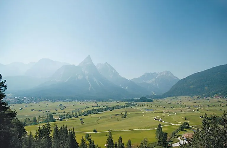 Rozsiahle údolie neďaleko Ehrwaldu s výhľadom na výraznú Zugspitze v pozadí počas jasného letného dňa.