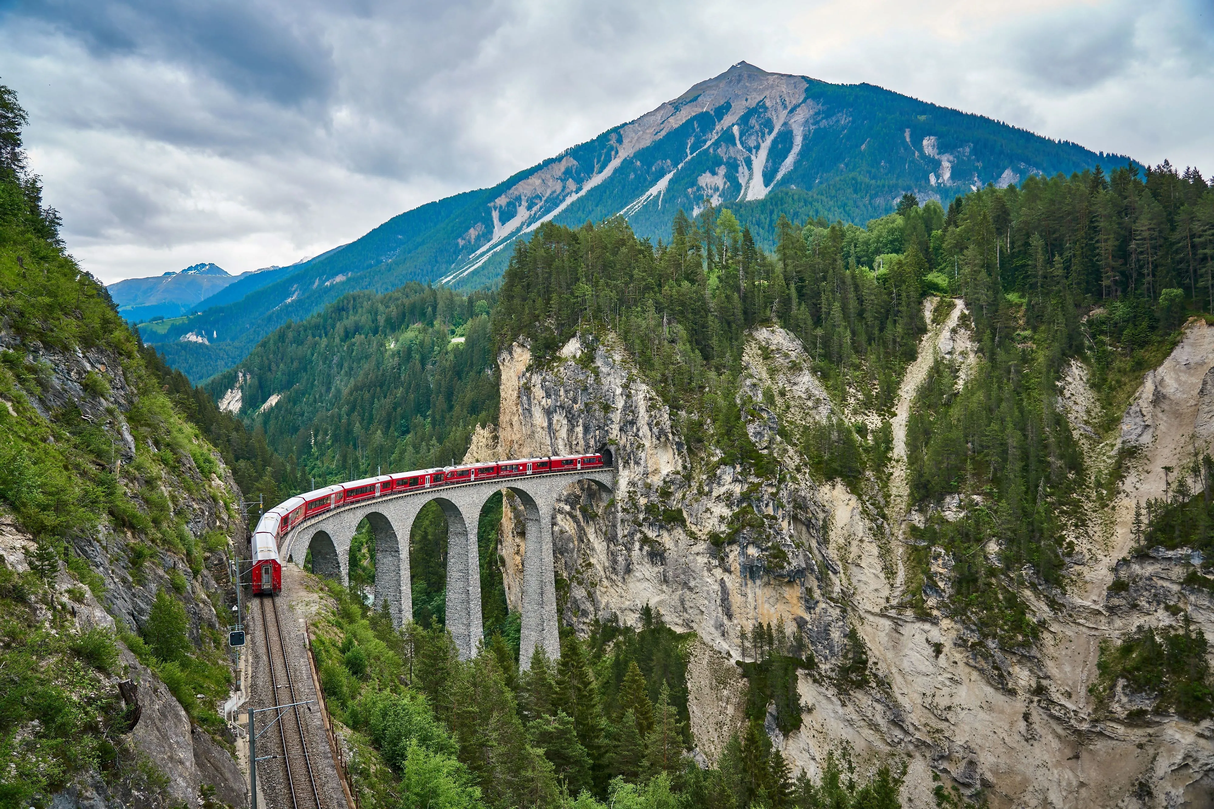 Bernina-Express auf einem Viadukt umgeben von spektakulärer Alpenlandschaft in Graubünden