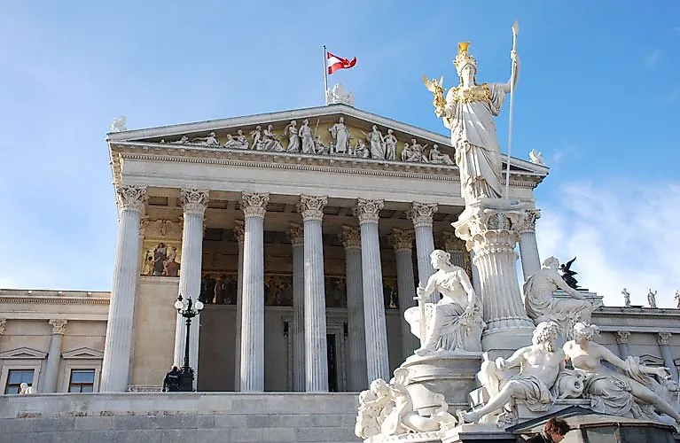 Das Parlamentsgebäude in Wien mit Pallas-Athene-Brunnen vor klarem Himmel.