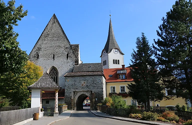 Hintereggertor medievale con chiesa e case colorate a Oberwölz in una soleggiata giornata estiva.