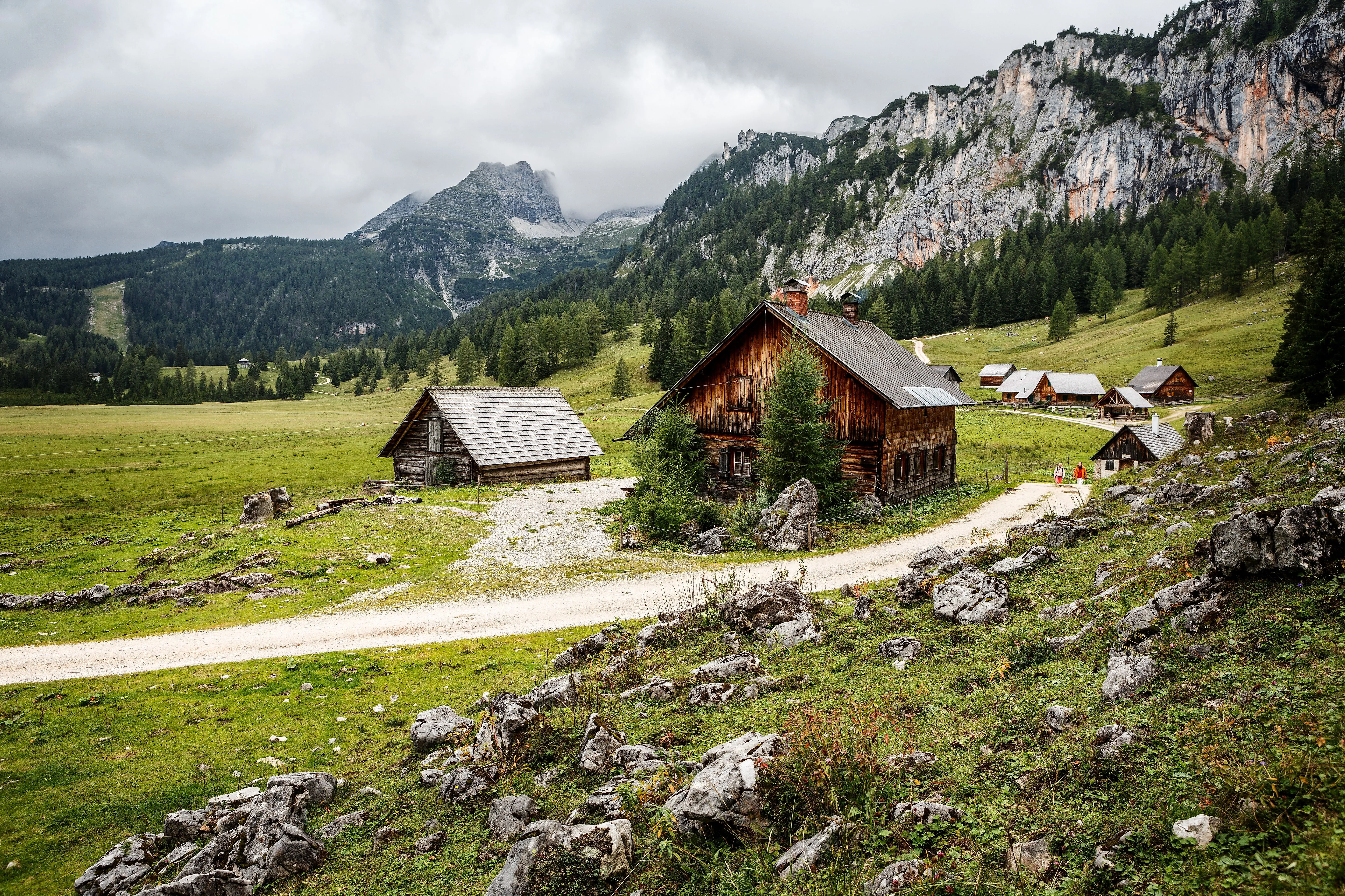 Traditionelle Almhütten auf der Wurzeralm bei Hinterstoder inmitten grüner Berglandschaft mit bewölktem Himmel.