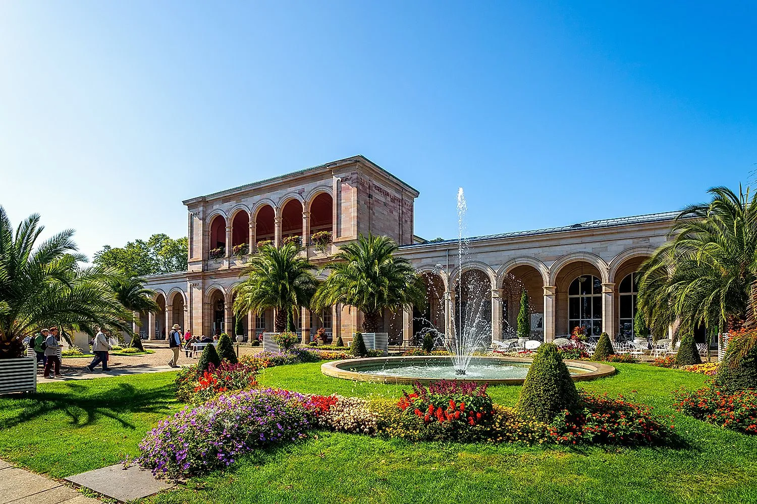 Kurpark Bad Kissingen mit Wandelhalle, Palmen und Brunnen bei Sonnenschein
