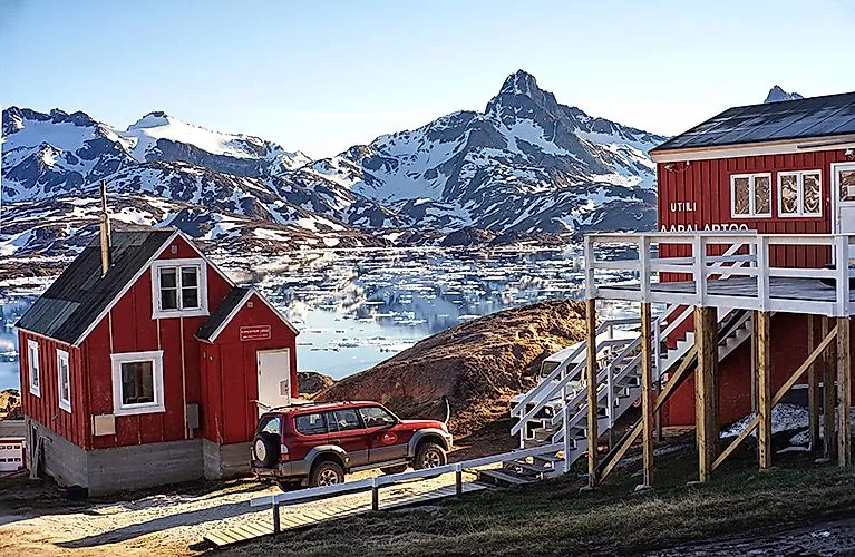 das Hotel "The Red House" mit roten Holzhäusern vor verschneiten Bergen in Tasiilaq, Ostgrönland