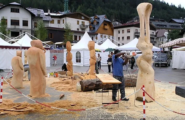 Un uomo scolpisce una scultura in legno nella piazza di Tarvisio in occasione dell'evento estivo di artigianato artistico