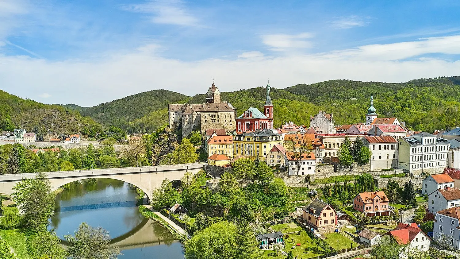 Blick auf die mittelalterliche Burg Loket und die farbenfrohe Altstadt im Grünen in der Nähe von Karlsbad