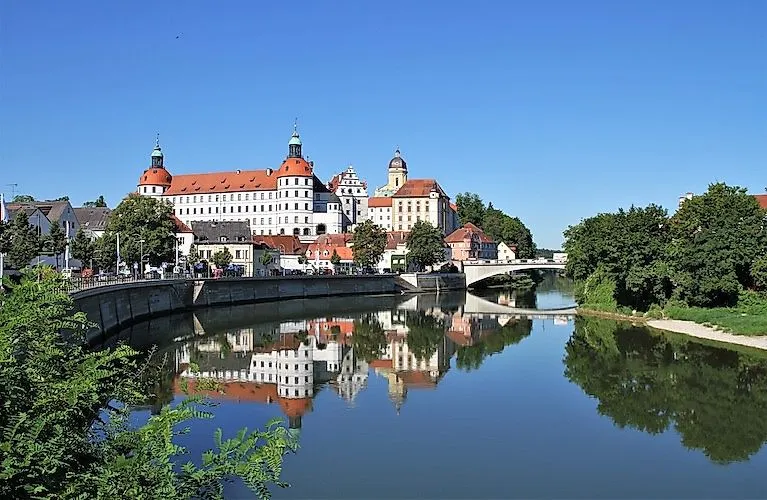 Blick auf Schloss Neuburg an der Donau mit Spiegelung in der Donau an einem klaren Sommertag
