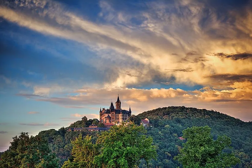 Märchenhaftes Schloss Wernigerode bei Sonnenuntergang auf einem bewaldeten Hügel im Harz.