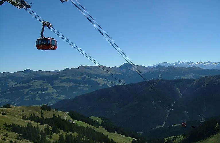 Rote Gondel der Seilbahn schwebt über den Berghängen von Kirchberg mit weiter Aussicht auf die Kitzbüheler Alpen.