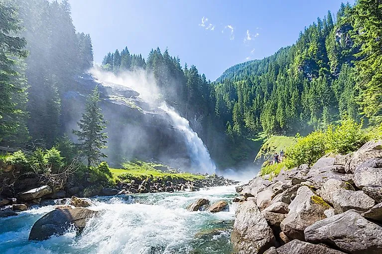 Eindrucksvoller Blick auf die Krimmler Wasserfälle inmitten grüner Wälder im Nationalpark Hohe Tauern.