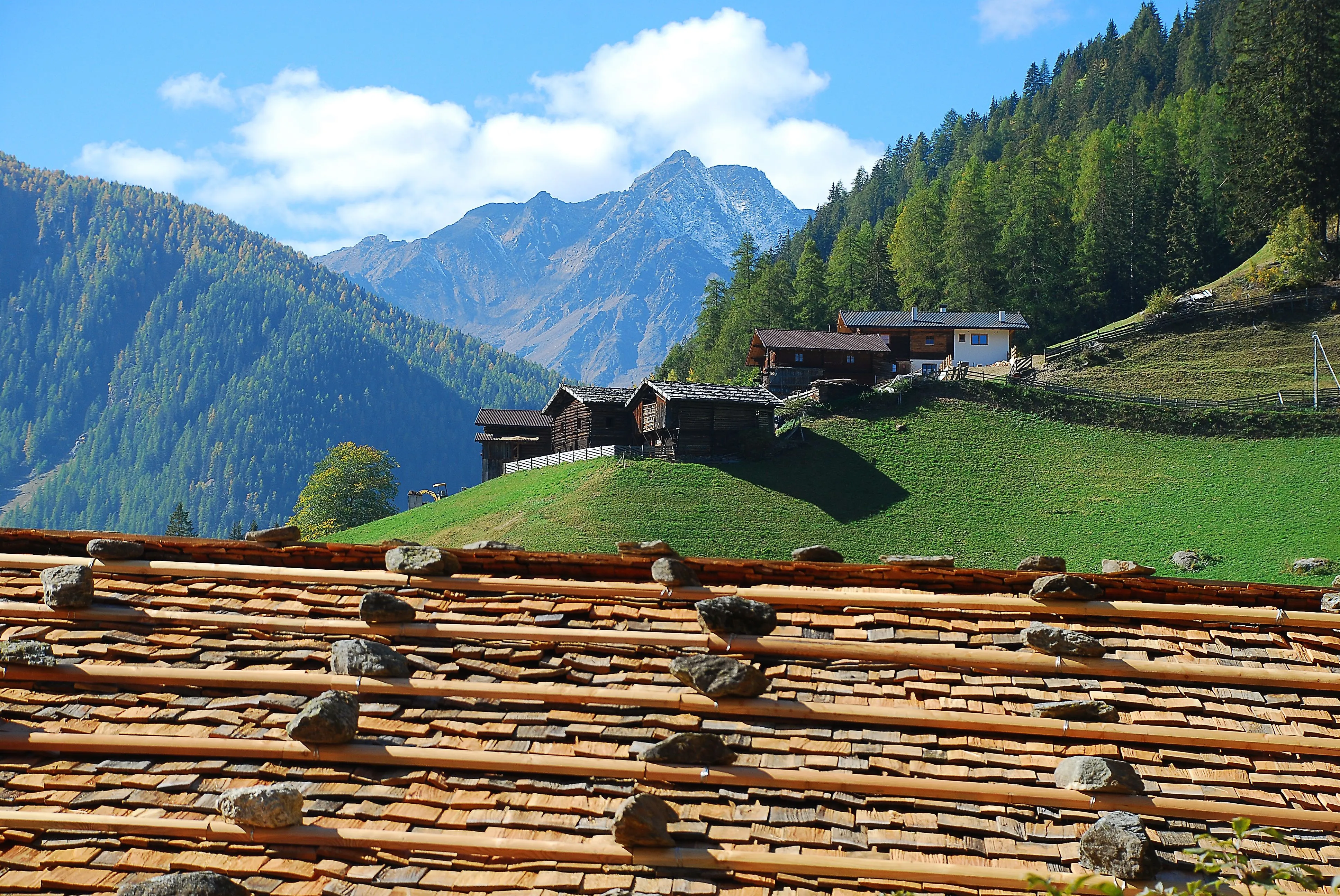 Historische Bauernhäuser im Ultental mit Blick auf die herbstlich gefärbten Wälder und Berge