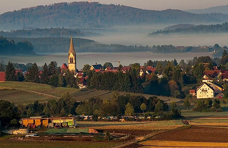 Blick auf Lautertal mit Kirchturm in morgendlicher Nebelstimmung, eingebettet in sanfte Hügel und Wälder