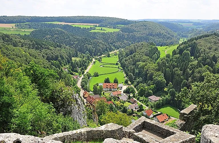 Panoramablick auf Lautertal mit grünen Wäldern, Wiesen und verstreuten Häusern – typisches Landschaftsbild der Schwäbischen Alb