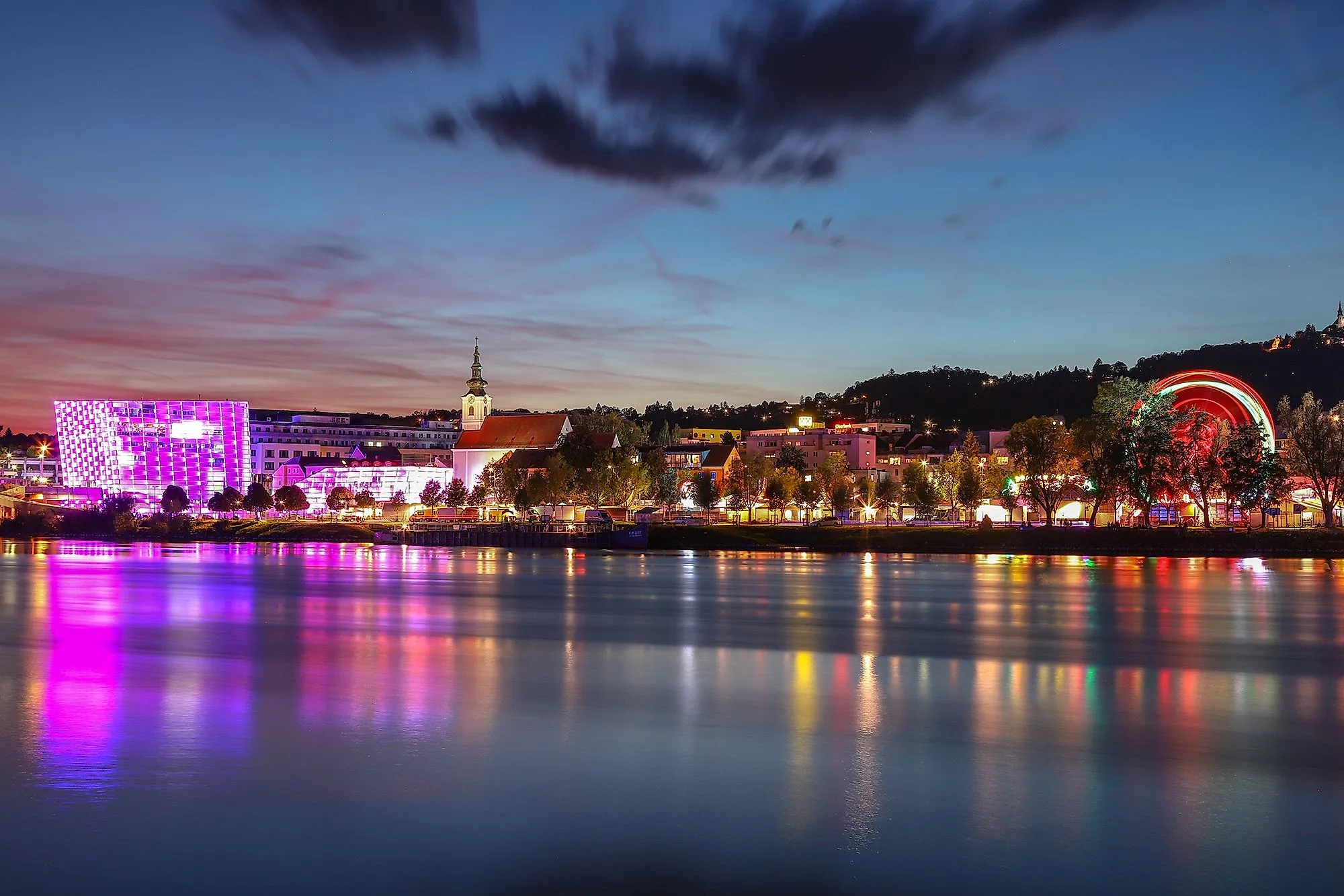 Imagen nocturna de Linz con el Danubio, el Centro Ars Electronica iluminado y el horizonte.