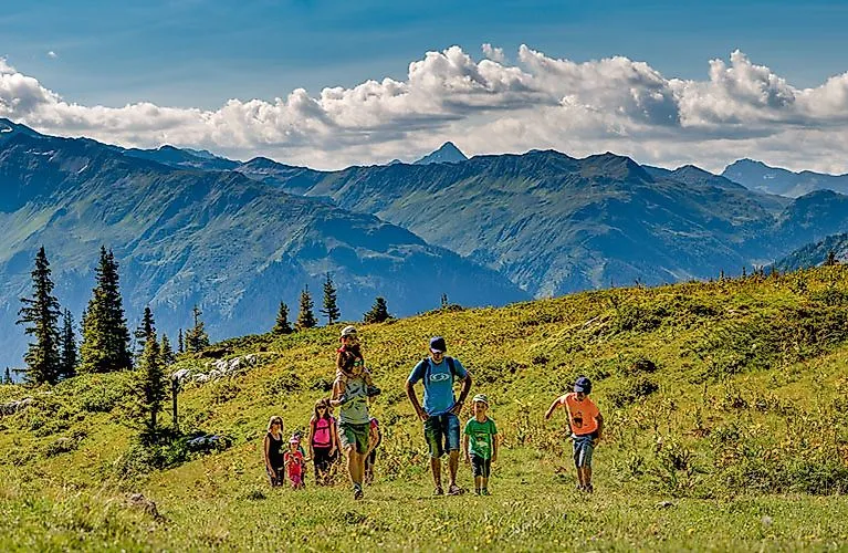 Familie beim sommerlichen Wanderausflug auf blühenden Almwiesen bei Klosters mit Blick auf die Berge