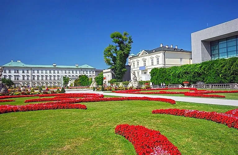 Blühende Beete im barocken Mirabellgarten mit Blick auf Schloss Mirabell und das Salzburger Landestheater