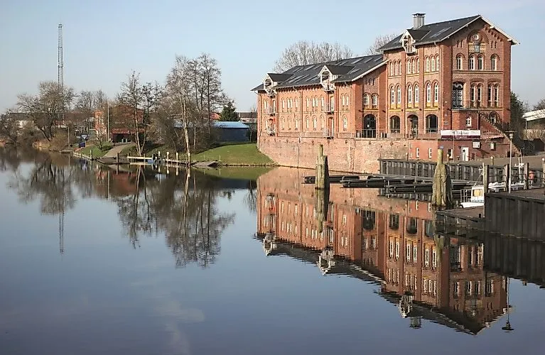 Historisches Zollhaus am Hafen von Norden mit Spiegelung im ruhigen Wasser des Kanals.