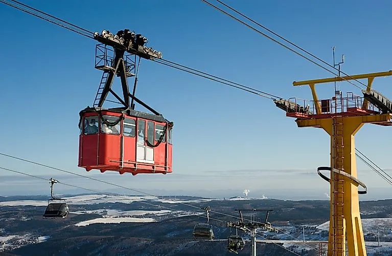 Rote Schwebebahn fährt über schneebedeckte Hügel in Oberwiesenthal mit weitem Blick über das Erzgebirge.