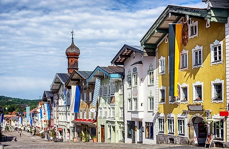 Bunte Häuserfassaden in der Altstadt von Bad Tölz im Sommer mit blau-weißen Fahnen.