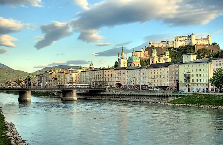 Blick über die Salzach auf die Altstadt von Salzburg mit barocken Türmen und der Festung Hohensalzburg im Abendlicht