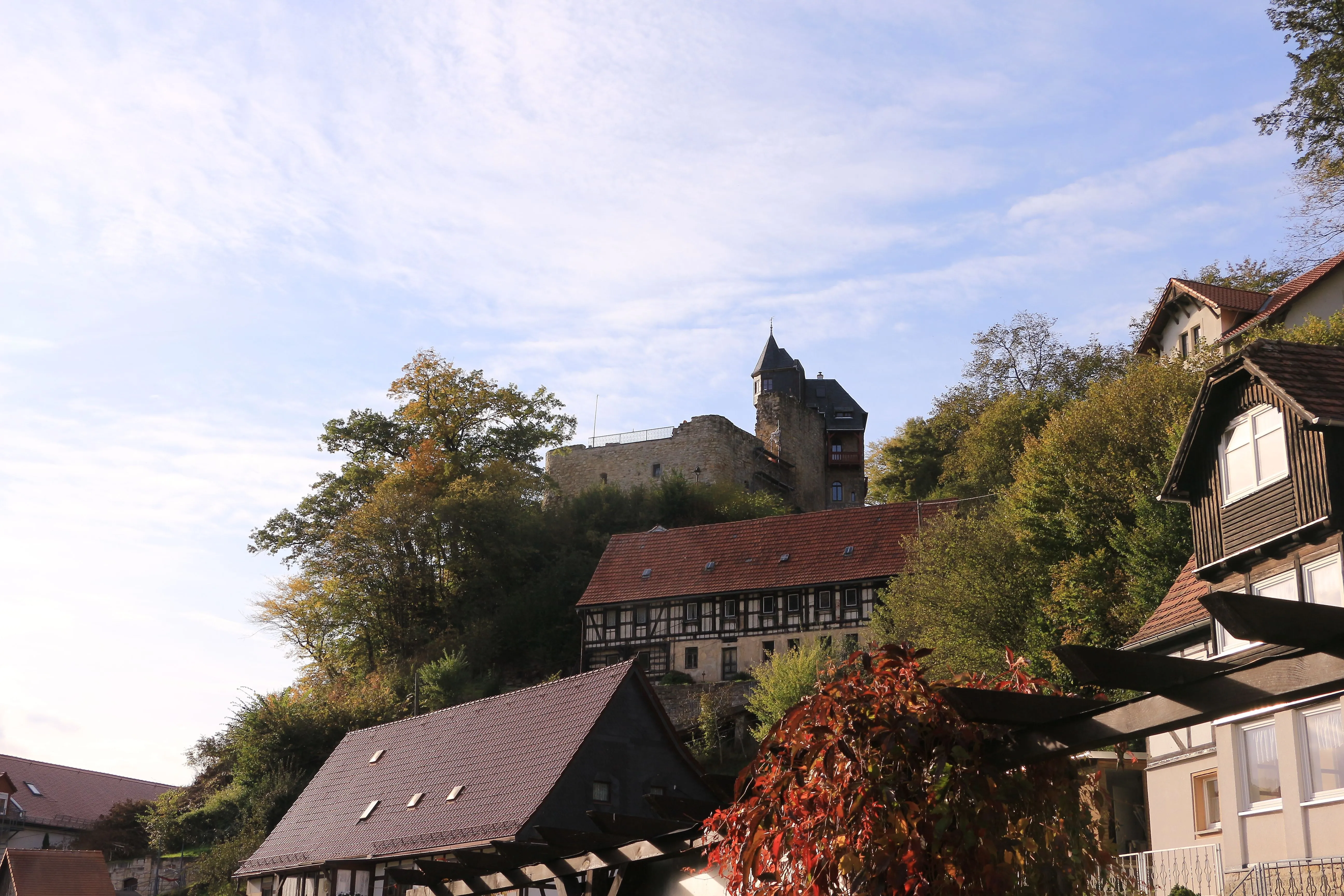 Die historische Burg Altrathen thront über den Dächern von Rathen und ist von herbstlich gefärbtem Wald umgeben.
