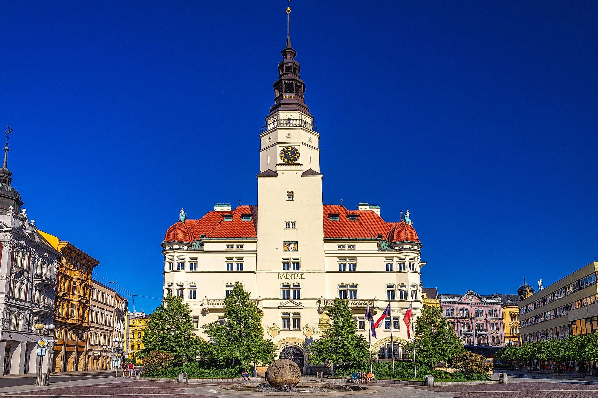 Historisches Rathaus in Opava mit Turm und Springbrunnen auf dem Stadtplatz bei Sonnenschein.