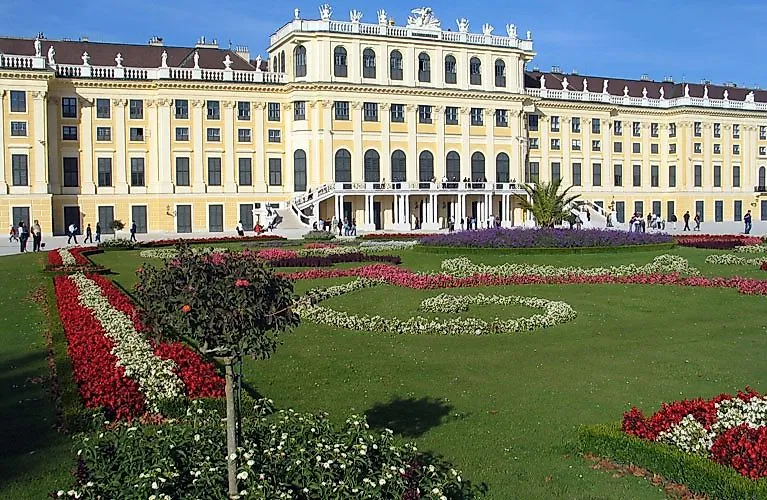 das UNESCO-Weltkulturerbe Schloss Schönbrunn mit barocker Fassade und Blumenbeeten im Vordergrund