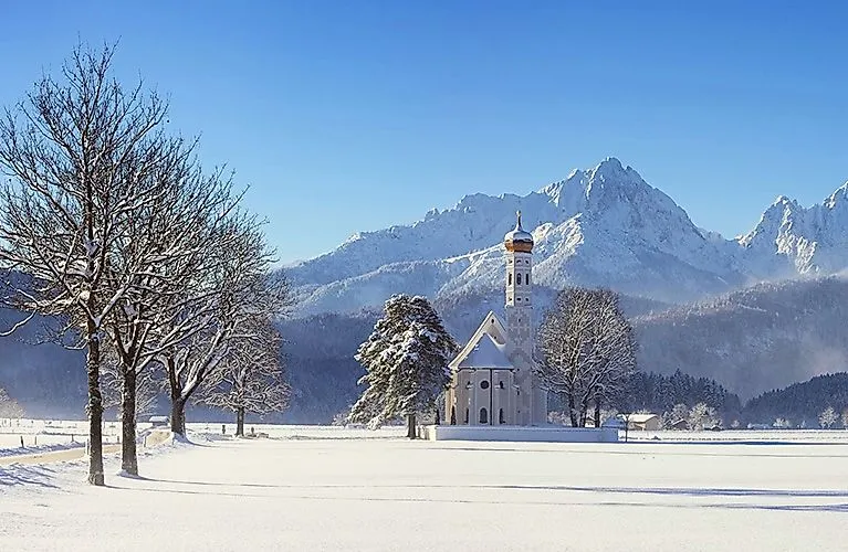 Barocke St. Coloman Kirche vor verschneiter Bergkulisse in Schwangau
