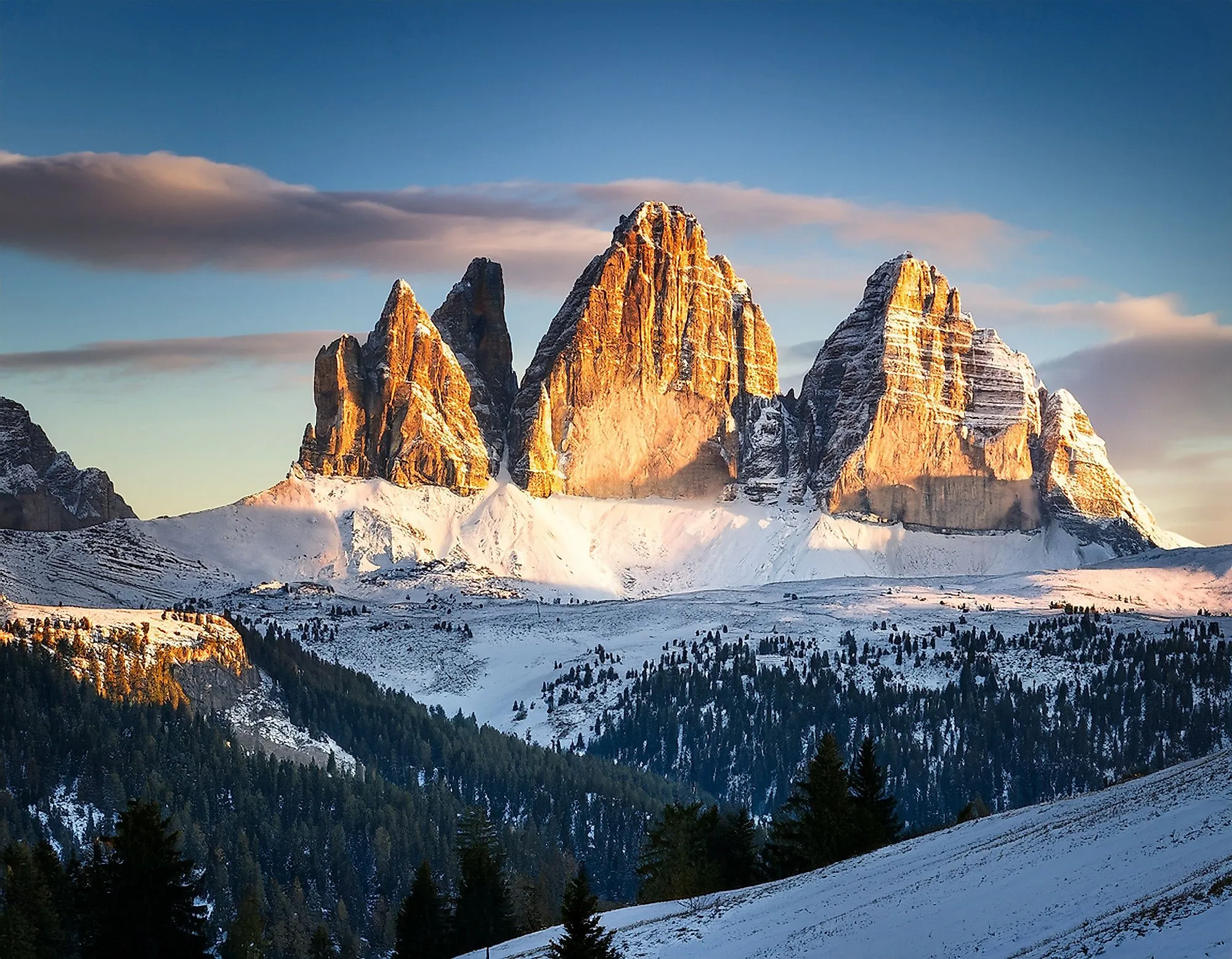 Winterlandschaft in Sexten mit Blick auf die verschneiten Drei Zinnen in den Dolomiten bei Sonnenuntergang