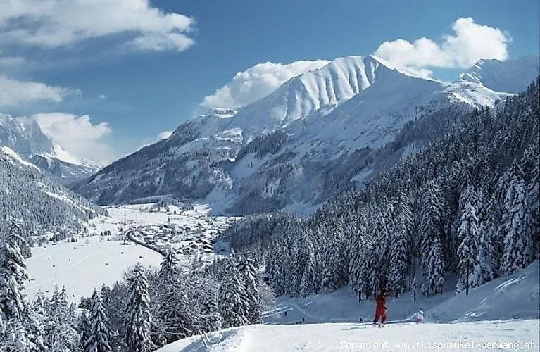 Panorama hivernal du domaine skiable de Berwang avec des pistes de ski enneigées, des skieurs et des montagnes majestueuses en arrière-plan.