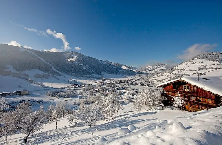 Tief verschneite Winterlandschaft mit Blick auf das Tal und ein Holzhaus in der Wildschönau