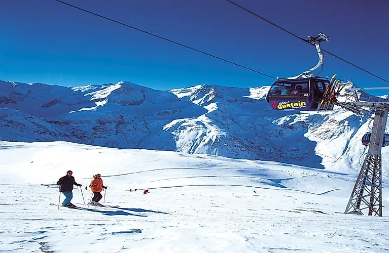 Skifahrer auf den verschneiten Pisten im Gasteiner Tal mit Blick auf die umliegenden Alpen.
