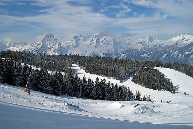 Schneesichere Pisten in Hinterstoder mit Ausblick auf die verschneiten Berge des Toten Gebirges im Winter.