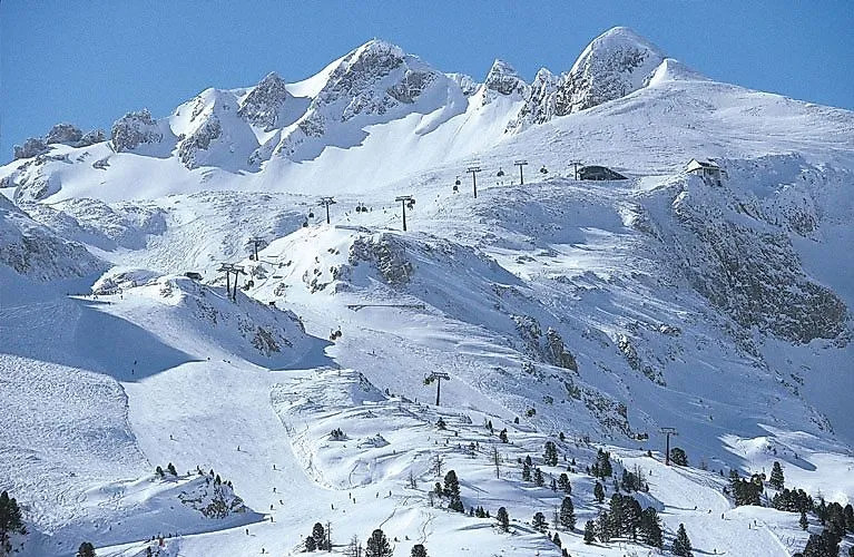 Schneebedeckte Gipfel und Pisten im Skigebiet Obertauern – mit Sesselliften, Skifahrern und traumhafter Winterkulisse inmitten der österreichischen Alpen.