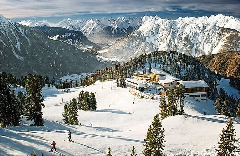 Skifahrer auf der Piste bei Oetz mit Panoramablick auf verschneite Berge und das Skigebiet im Ötztal.