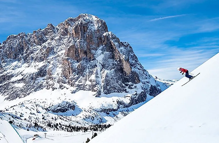 Skifahrer in St. Christina Gröden vor beeindruckendem Langkofel-Massiv in den Dolomiten.