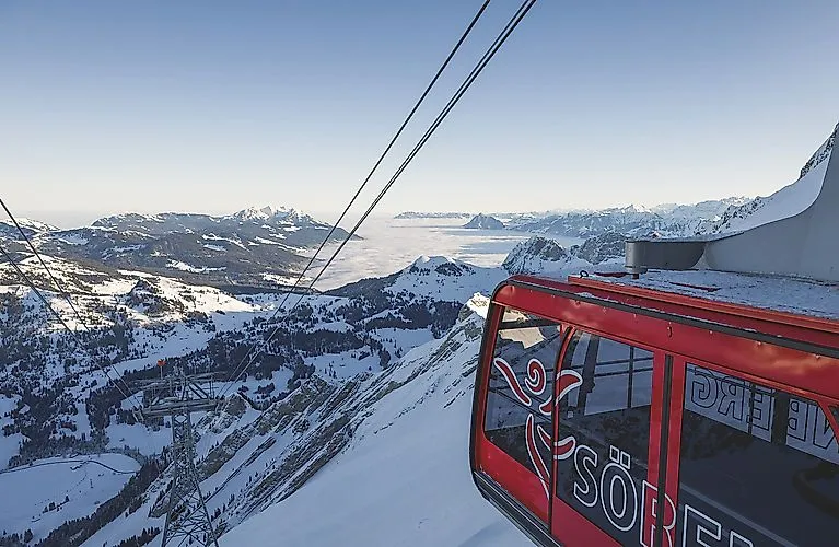 Rote Gondel der Luftseilbahn Sörenberg vor schneebedeckter Alpenkulisse und weiter Aussicht über das Nebelmeer.